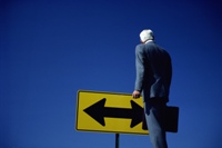 Choices: photo of a business man in front of a traffic sign, illustrating trying to make the right choices.